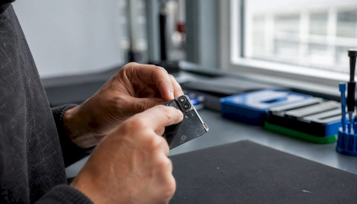 Handen die een onderdeel van een Apple-apparaat nauwkeurig bekijken