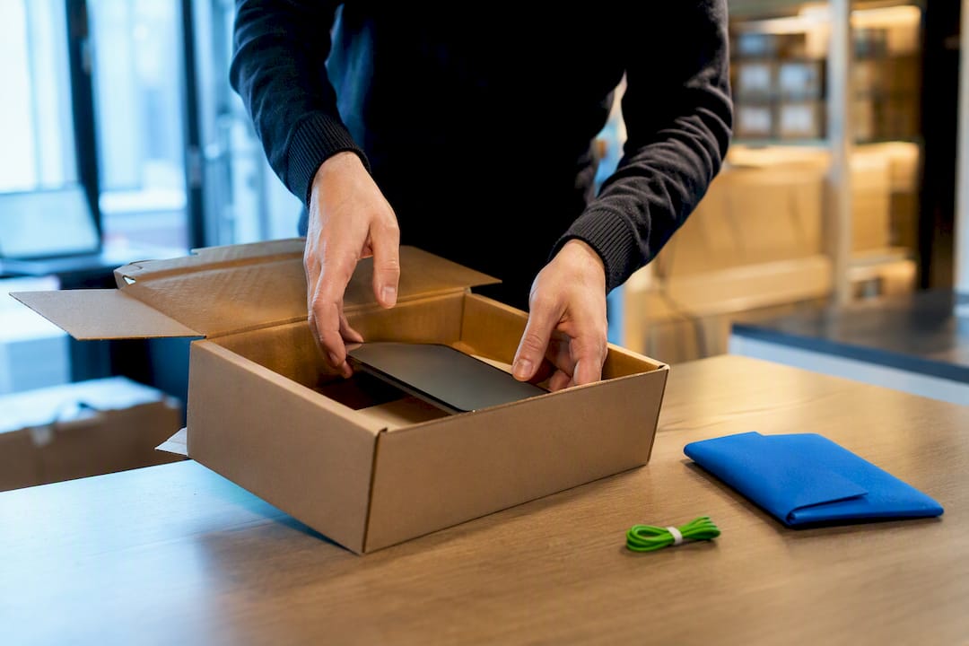 Handen verpakken een refurbished apparaat voor verzending