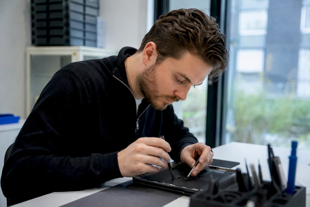 Een close-up van handen die bezig zijn met het vervangen van een iPad-scherm.