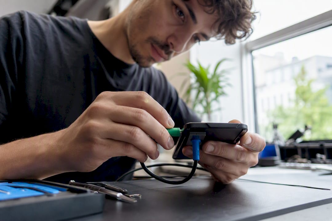 Vakkundige handen die een smartphone onderzoeken en repareren
