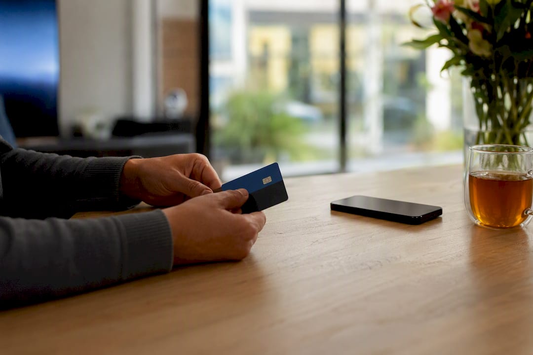 Hand die een betaalkaart vasthoudt bij een smartphone