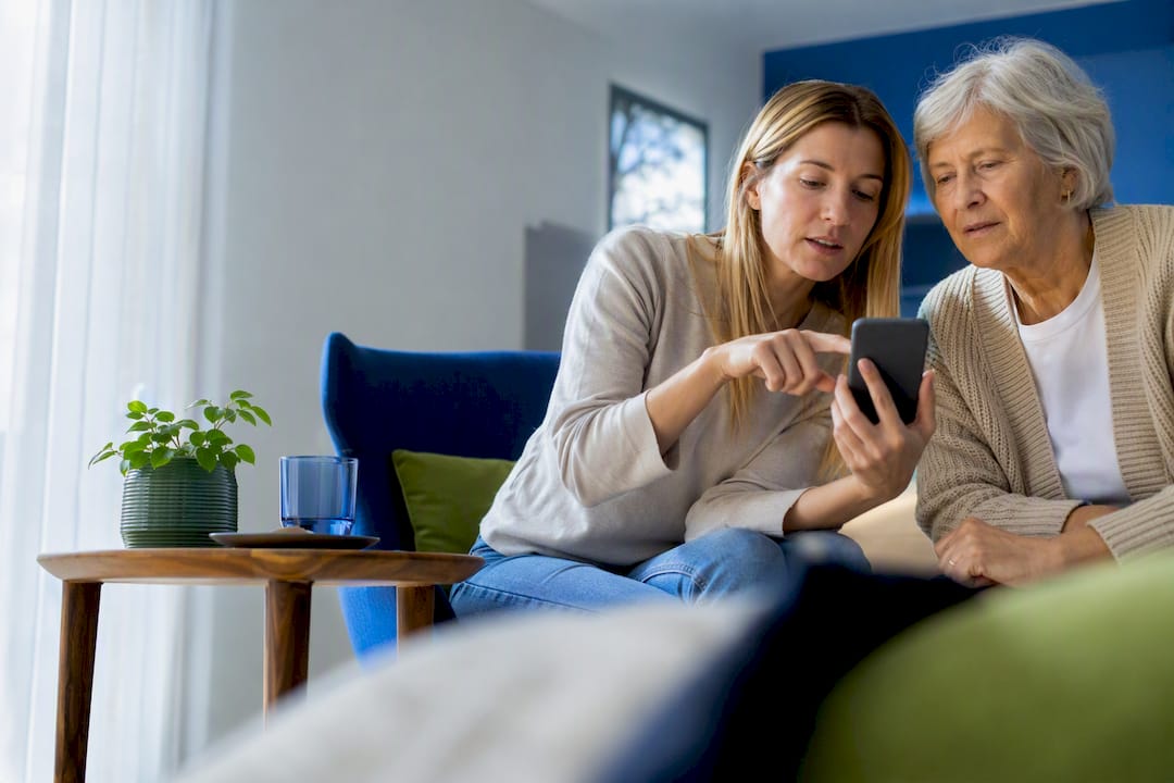 Mantelzorger helpt oudere met het instellen van de smartphone